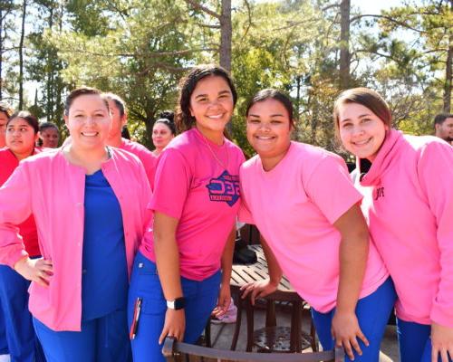Nursing students stand to make a human pink ribbon in middle of campus